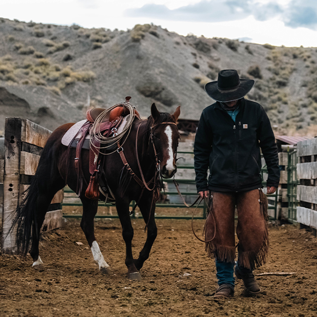 A cowboy walking with a horse.