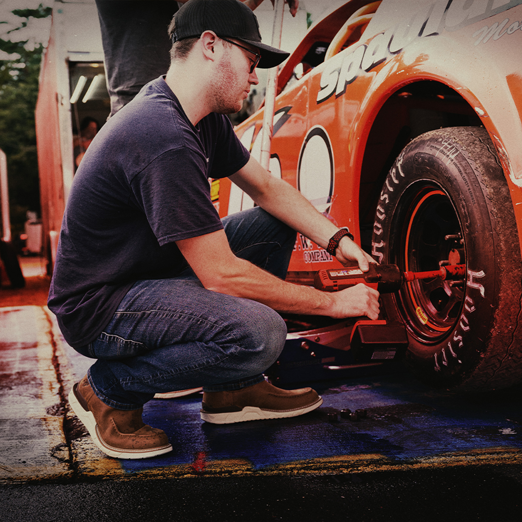 A man working on a car and wearing the Amos chelsea boots in brown.