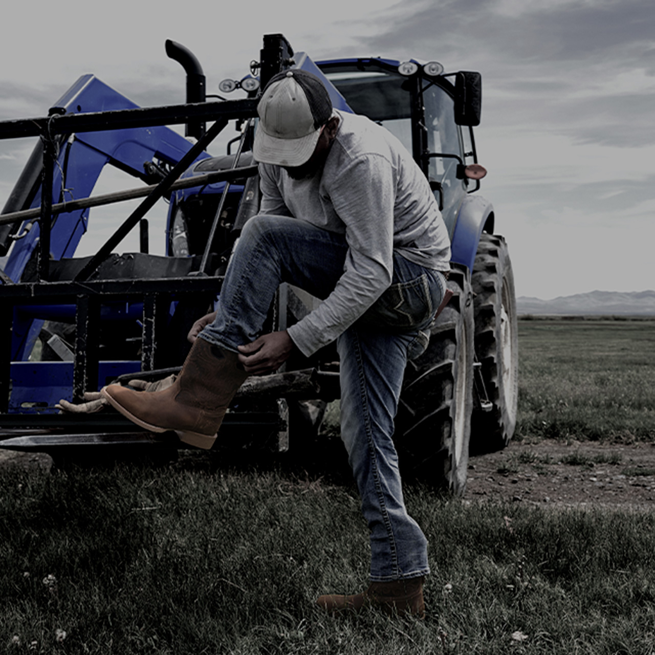 A man wearing Phantom Rider boots outside next to a tractor.