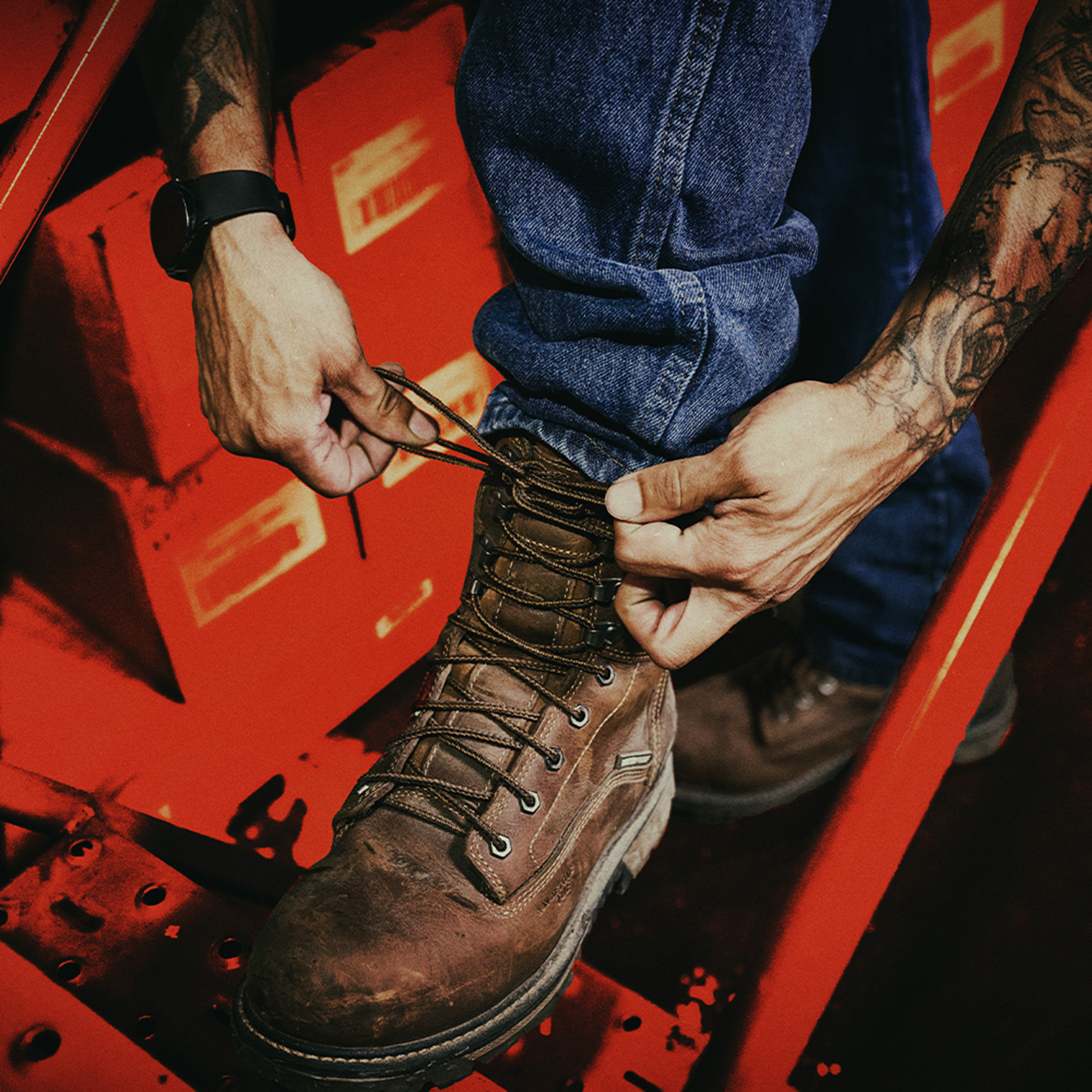 A man lacing up the Piston 8" Comp Toe in brown.