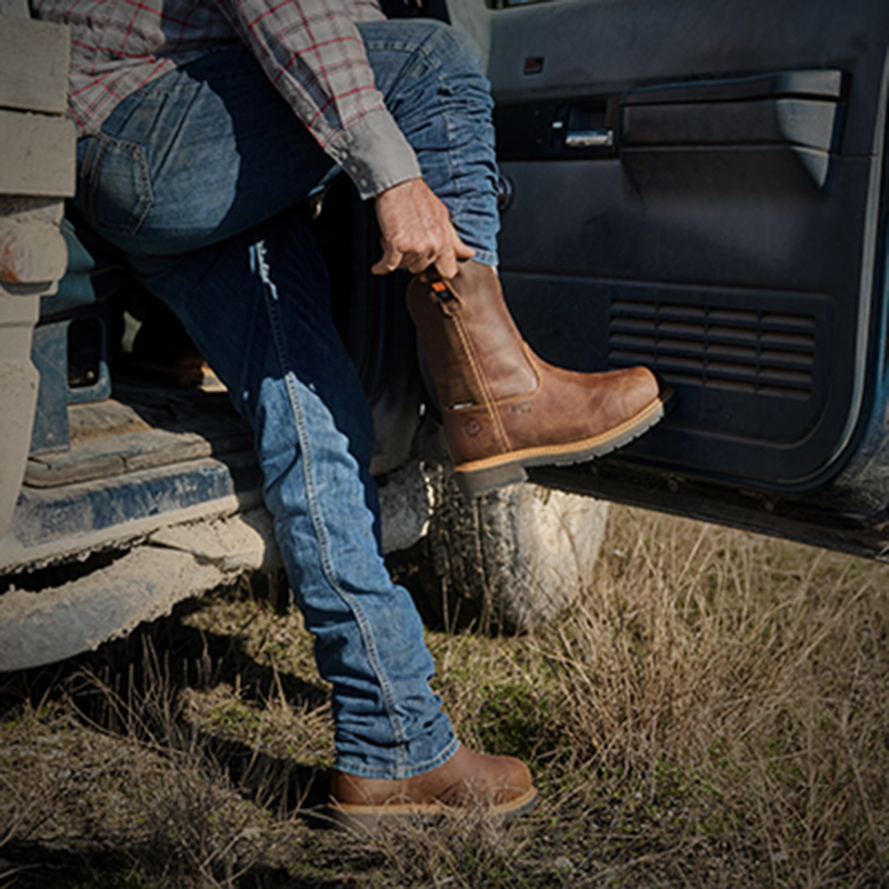 A man pulling on the Boss Alloy Toe in brown.
