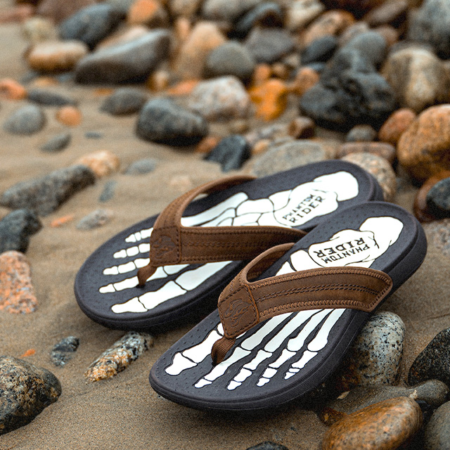 The Phantom Rider Phlip Phlops in brown sitting on the beach.