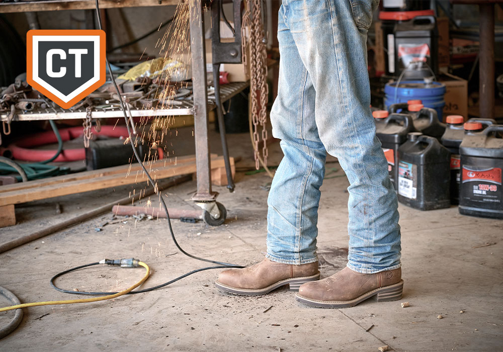 A cowboy working and wearing the Garza comp toe western boot in brown. CT (Comp Toe) feature badge.