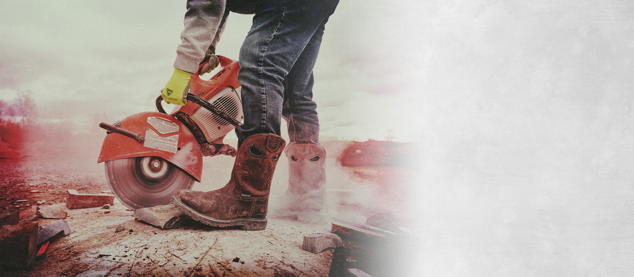 A person wearing the Dustie Comp Toe western boot in brown and using a circular saw on a log.