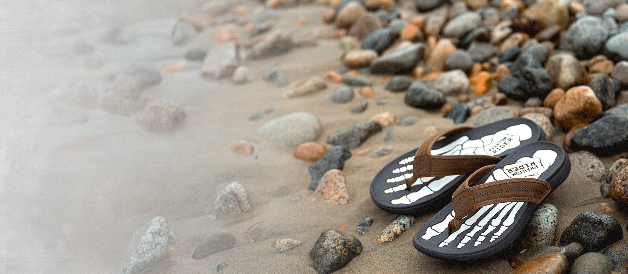The Phantom Rider Phlip Phlops in brown sitting on the beach.