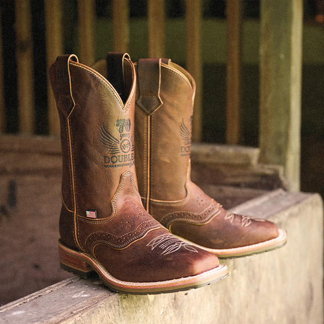 The 70th Anniversary roper boots in brown sitting in a barn.