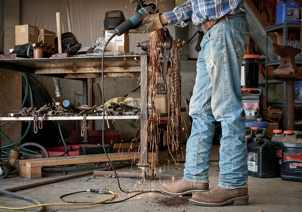 A man working and wearing the Garza Comp Toe western boot in brown.